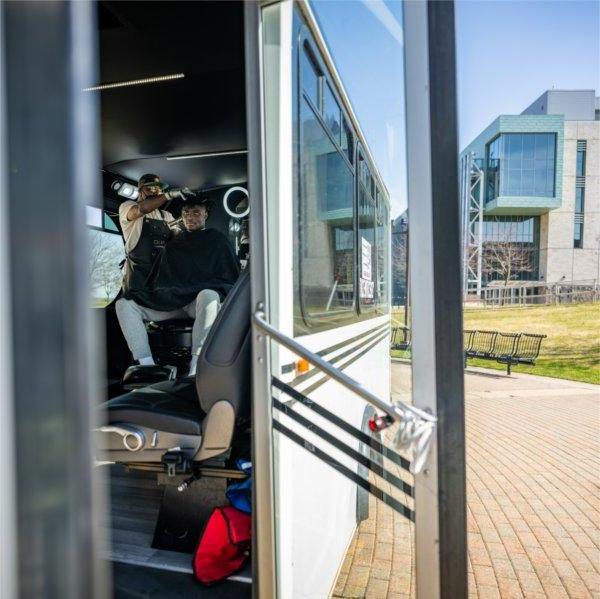 Cecil Jackson gives a haircut to a student in his barber van parked on the Allendale Campus.