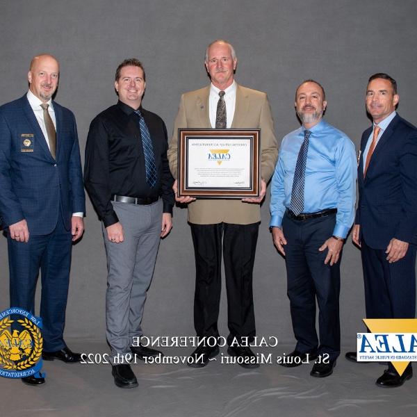 Grand Valley and CALEA officials pose with GVSU's CALEA law enforcement certificate.