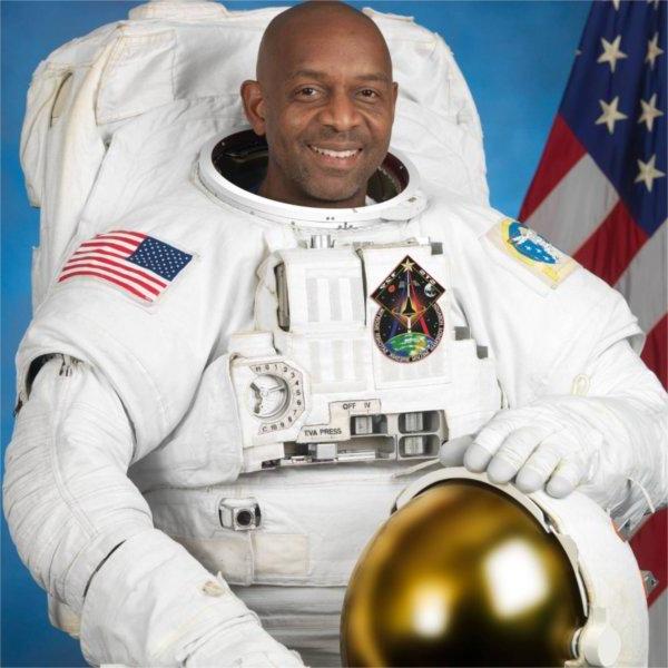 A person in an astronaut uniform smiles for the camera.