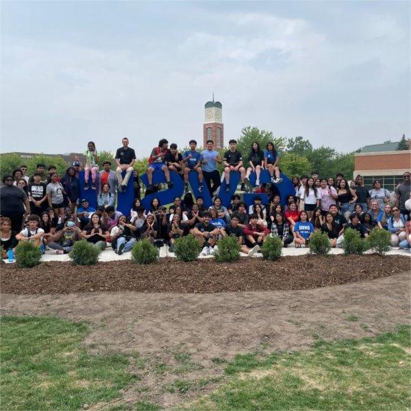 large group of students, staff sitting and standing near the GVSU letters